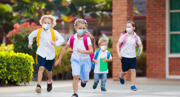 Young children running outside with facemasks