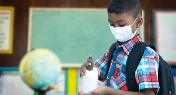 Young Boy wearing facemask and using hand sanitizer